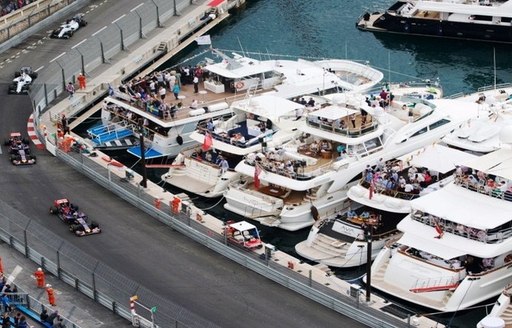 Yachts overlooking the race track at the Monaco Grand Prix as four cars race past