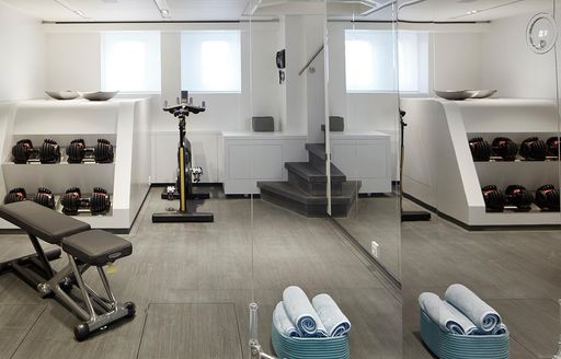 the fully equipped gym in charter yacht HOME with windows and large mirror 