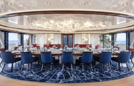 Formal dining area onboard charter yacht AHPO, long dining table surrounded by blue seats