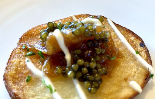 black caviar being served on board yacht on potato latke 