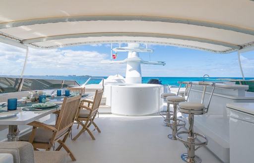 Charter yacht XOXO flybridge overview with seating area and wet bar with stools