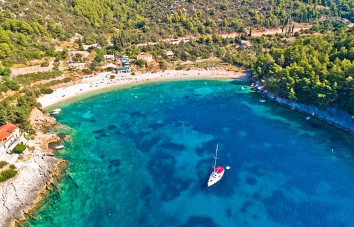 little blue bay in croatia with green hills in background