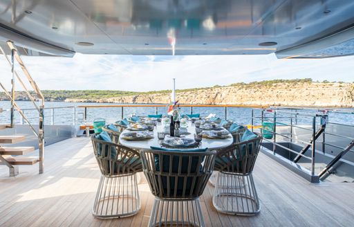 Exterior dining area with long table and sea views onboard charter yacht PANDION PEARL