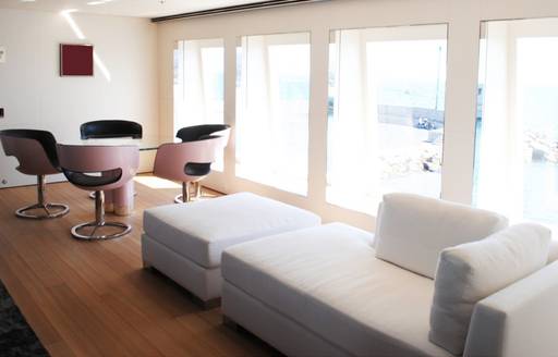 Interior seating area with chaise longue, adjacent to dining table onboard charter yacht AIR