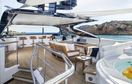 charter yacht irisha's sun deck with spa pool in foreground and dining and wet bar in background 