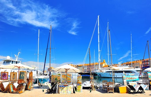 artists easels opposite yachts in harbour in france against blue sky