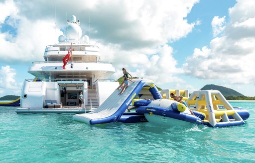 inflatable water park and obstacle course in the sea in thailand with view of lurssen motor yacht titania in background