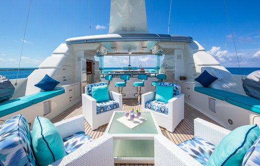 Alfresco seating area with white chairs and blue cushions onboard yacht rental NITA K II