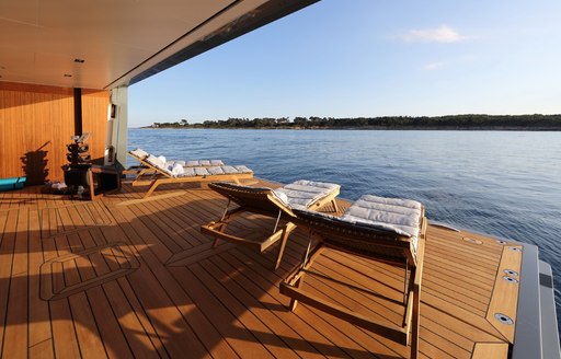 beach club and swim platform on admiral yachts planet nine, with sun loungers lined up next to the water