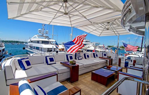Aft deck of a superyacht charter with white seating and blue cushions