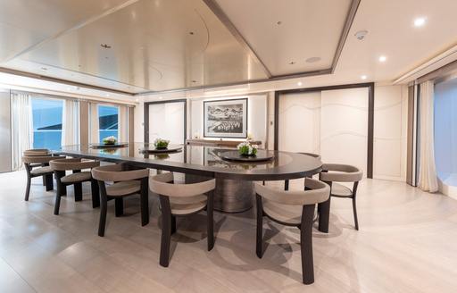 Dining room with long table and gray chairs onboard charter yacht LUNA