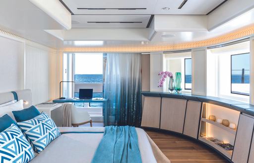 Overview of master cabin onboard charter yacht RIO with berth in foreground and a desk by a large window