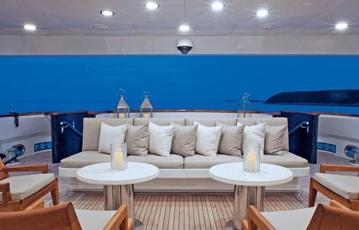 social seating on main deck aft of luxury motor yacht alessandra, with sofas in front of cocktail tables with candles in centre