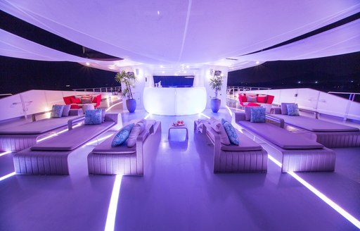 Lit up sun deck of SALUZI with seating and jacuzzis on board charter yacht SALUZZI