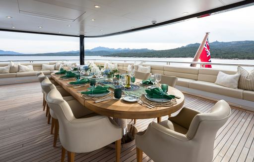 Exterior dining table with green place settings onboard charter yacht STARFIRE