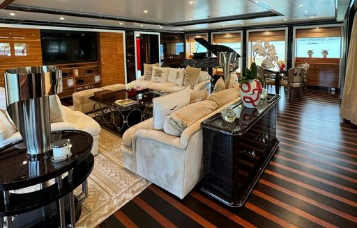 Interior lounge area with plush sofas and a grand piano aft onboard superyacht charter ALFA NERO