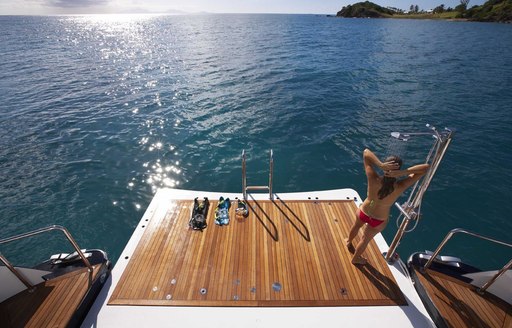 a charter guest showers on the swim platform of superyacht DESTINY