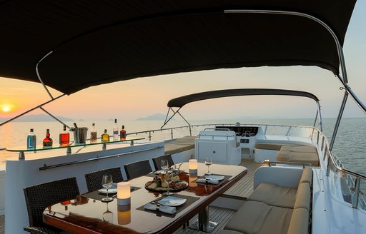 Sundeck on luxury yacht Mia Kai, with wet bar lined with drinks and alfresco dining set-up