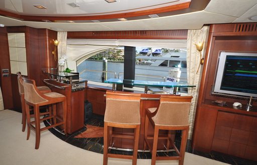 Interior wet bar onboard boat charter VIVERE with four stools looking out a large window