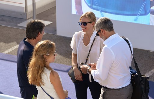 Group of show-goers stand with yacht broker at Cannes Yachting Festival