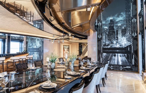 Interior dining area onboard superyacht charter KISMET, long black table surrounded by white upholstered chairs