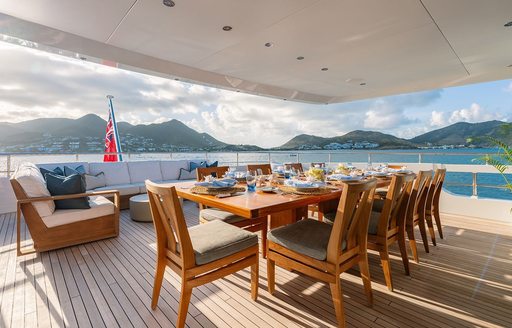 Long wooden table and padded chairs on the aft deck of charter yacht MOSKITO