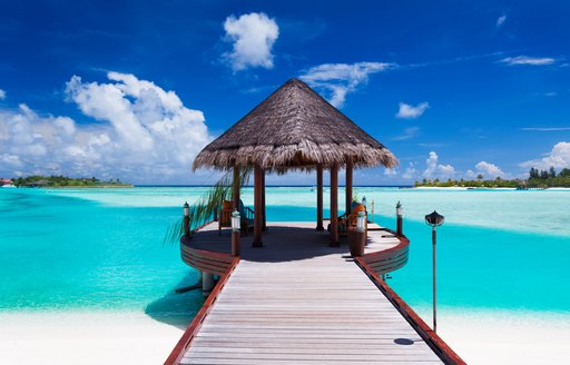 Wooden pier stretching out over turquoise waters in the maldives