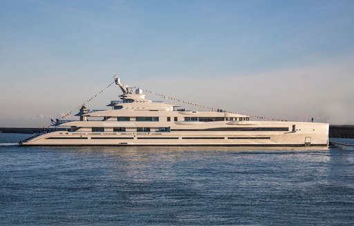 Benetti's motor yacht LANA as she cruises the waters of the Caribbean at dusk with her guests celebrating on the beach cl;ub