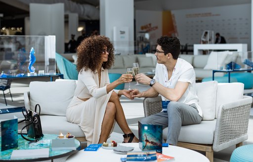 A couple toasting champagne glasses in the Upper Deck Lounge and Bar at the Monaco Yacht Show