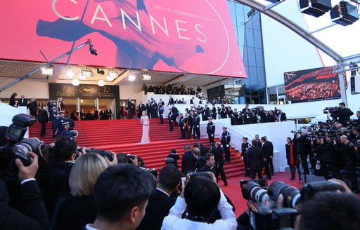 Steps covered by red carpet leading to Cannes Film Festival venue- the Palais des Festivals- with superyachts in background