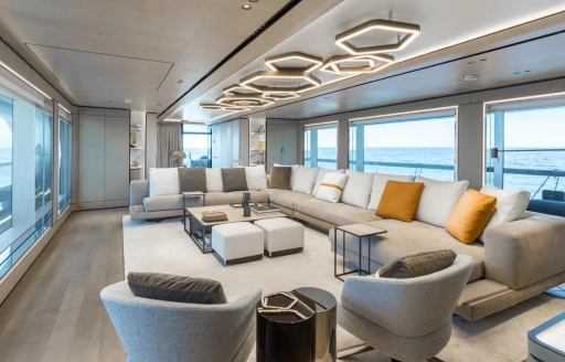 Overview of the main salon lounge area with white seating and yellow scatter cushions onboard yacht charter AKULA