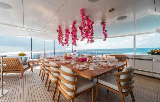 Luxury yacht charter CAPTAIN MORGAN III exterior dining table and pink flowers