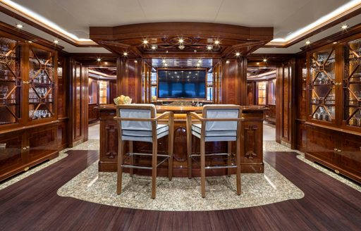 Interior wet bar with a pair of stools and dark wood onboard charter yacht STARFIRE
