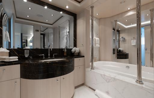 Ensuite facility with black sink unit and large bath onboard charter yacht ETERNITY