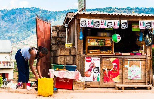 A woman bends over to tend to a bucket outside of a wooden store