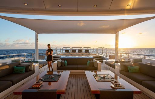 the aft skylounge of a superyacht with a lovely crew member taking every bit of caution during this pandemic so the guests of a luxury yacht charter have a relaxing and stress free vacation