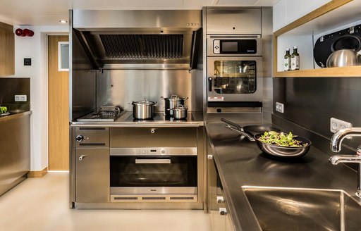 Stainless steel galley of Game Changer yacht with oven and pots on hob visible