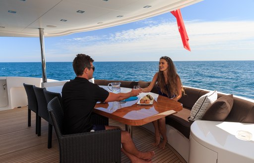 Charter guests enjoy a drink on aft deck alfresco dining area on board motor yacht Paradise 