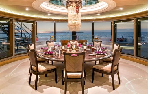 Interior dining area with circular table dressed for a meal onboard charter yacht AMARYLLIS