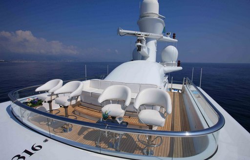 Observation deck onboard charter yacht NOMAD, four stools in the foreground with white seating aft