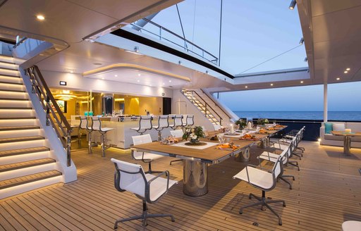 social area on aft deck of luxury charter yacht aquijo,with large dining table and alfresco bar