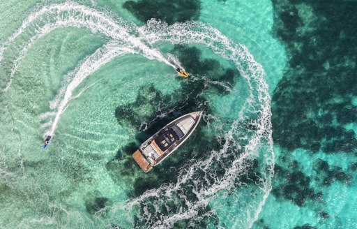 Two e-boards power around a small boat in the water