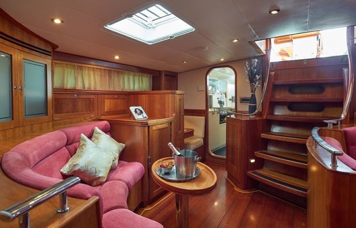 Interiors onboard sailing yacht charter DARK STAR OF LONDON, with curved seating bench and a table with a wine bucket