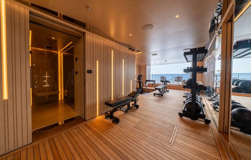 Charter yacht SYMMETRY beach club interior with gym equipment