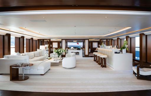 Interiors onboard superyacht charter SOPHIA with a cream sofa to port and a wet bar with stools starboard