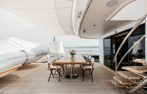 Exterior dining area onboard charter yacht HEEUS with adjacent stairs leading to upper deck