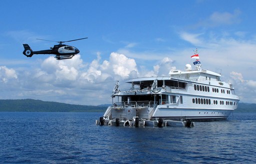 helicopter hovering above motor yacht True North when on a luxury yacht charter in the Whitsundays