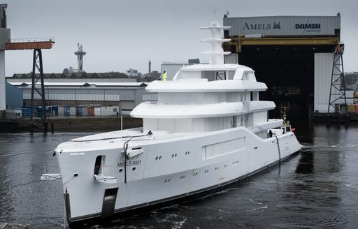 Frontal view looking at the bow of the first Amels 80 outside a construction shed