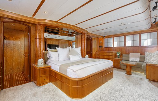 Master cabin onboard charter yacht ALMOST THERE, with forward facing berth and a seating area in the background 