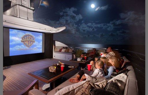 Sundeck cinema onboard Superyacht LIND, widescreen facing sofa seating at night, surrounded by sea